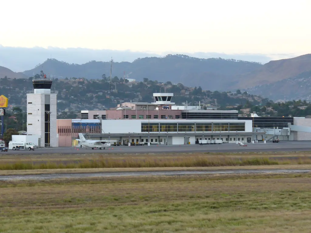 Terminal del aeropuerto Toncontín con su torre de control, una avioneta en la plataforma y los cerros de Tegucigalpa al fondo