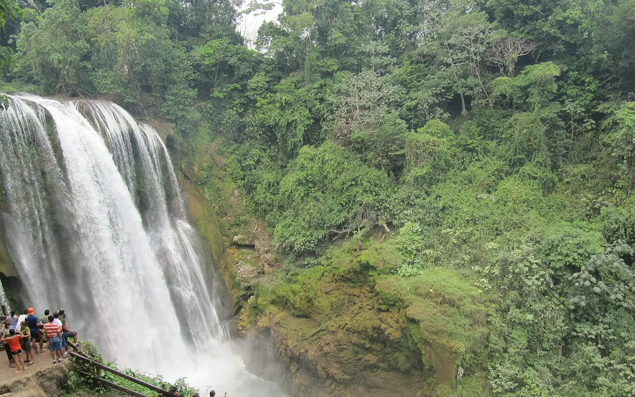 Catarata de Pulhapanzak cayendo entre la selva, con un grupo de visitantes en el mirador de la izquierda
