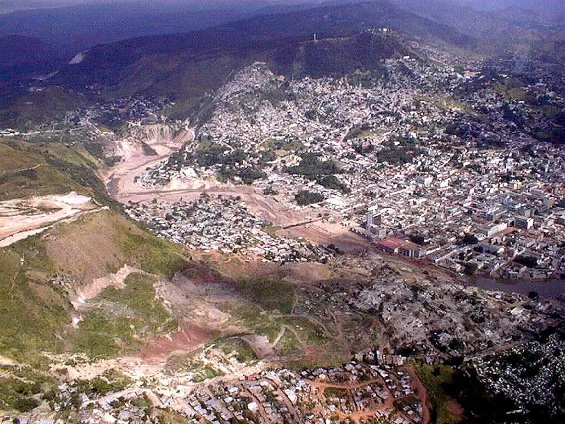 Vista aérea de Tegucigalpa con cerros pelados por deslaves, una franja ancha de lodo claro donde corre el río y barrios de casas apiñadas a los lados
