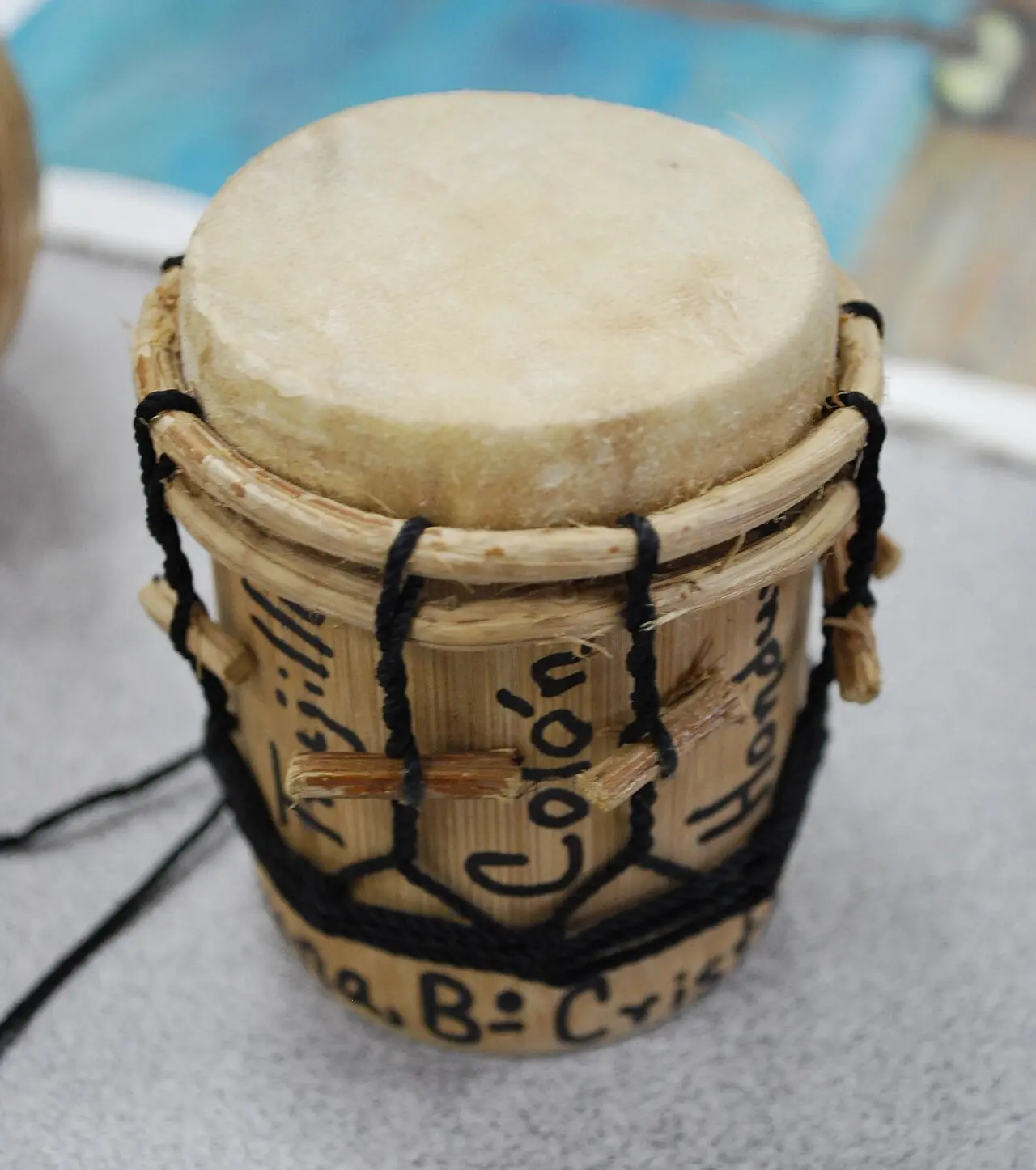 Tambor garífuna en miniatura hecho a mano, con parche de cuero, aro de bejuco y cuerdas negras tensadas con palitos, con las palabras Trujillo, Colón y Honduras escritas en la madera